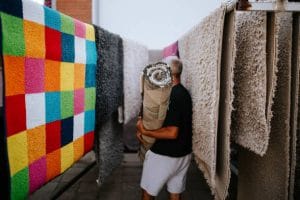an elderly man in a carpet cleaning company takes a washed carpet to dry